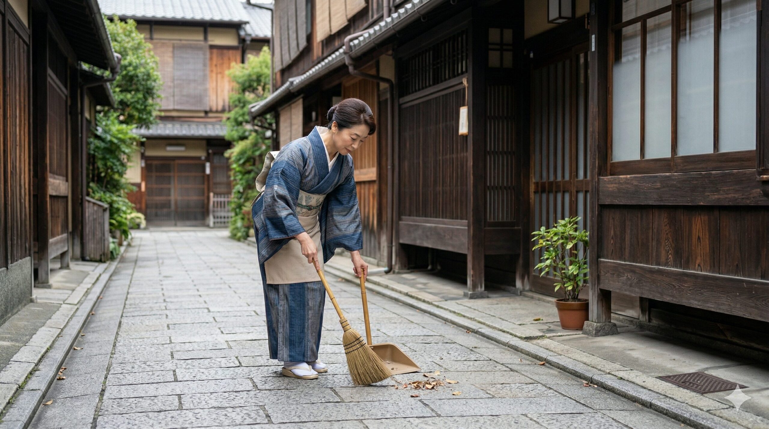 京都の伝統的な町家の前で、和服姿の日本女性が隣の家の前まで丁寧に門掃きをする様子