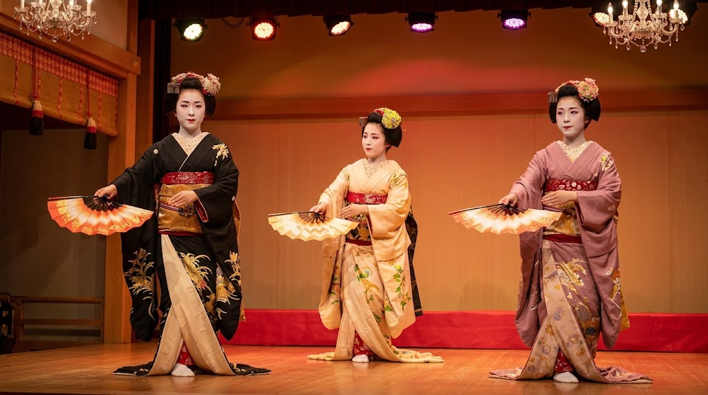 祇園会館の祇園をどり舞台で、華やかな着物を着た3人の日本人芸妓と舞妓が、扇を持って優雅に舞を披露する様子。
